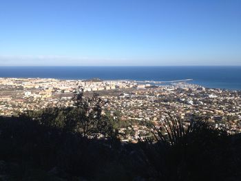 High angle view of townscape by sea against blue sky