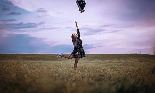 Woman with arms raised on field against sky