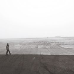 Full length of man walking at airport runway during foggy weather