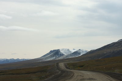 Road leading towards mountains against sky