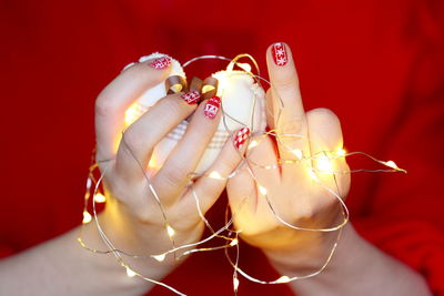 Midsection of woman holding illuminated string light with heart shape decoration