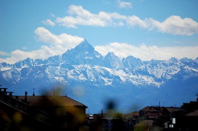 Houses and snowcapped mountains against sky