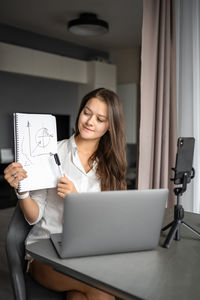 Young woman using laptop while sitting on table