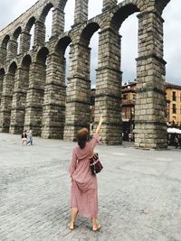 Rear view of woman leaning on historical building