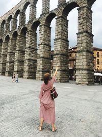 Woman standing against historic gate in city