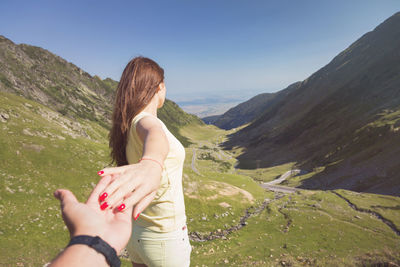 Cropped image of man holding girlfriend hand on mountain