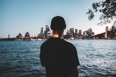 Rear view of silhouette man standing by sea against clear sky