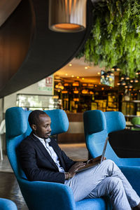 Businessman using laptop while sitting on chair at modern bar