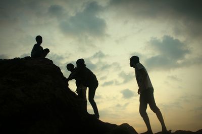 Low angle view of silhouette people standing on mountain against sky