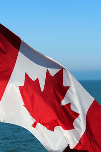 Canadian flag on lake against clear blue sky