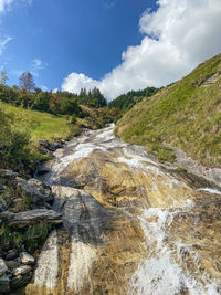 Stream flowing through rocks against sky