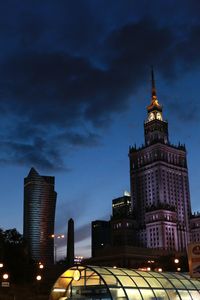 Palace of culture and science and modern building against sky at dusk