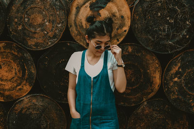 Young woman standing by stack of firewood