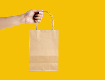 Midsection of woman holding paper against yellow background