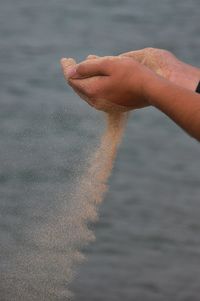 Close-up of hand with sea in background