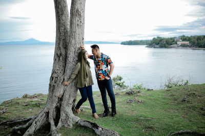 Couples standing on tree trunk by lake