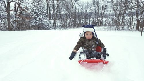 Baby boy sitting on snow covered field