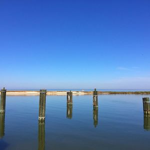 Wooden bridge over lake against clear blue sky