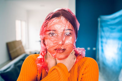 Portrait of teenage girl with plastic bag covering face standing at home