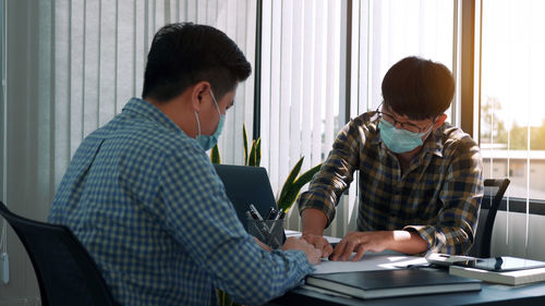 Business persons wearing mask sitting at office