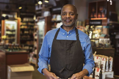 Portrait of smiling senior owner standing in store