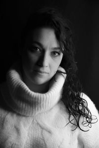 Portrait of young woman against black background