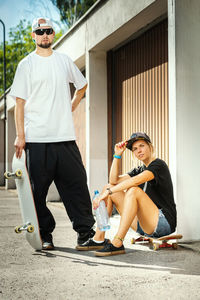 Portrait of couple with skateboards in city