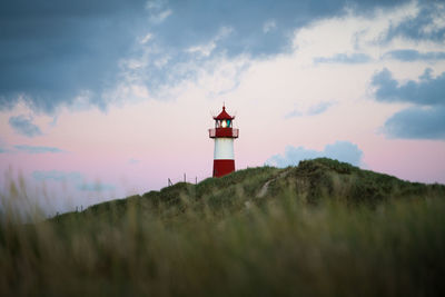 Lighthouse on field against sky