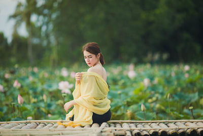 Woman holding umbrella standing against plants