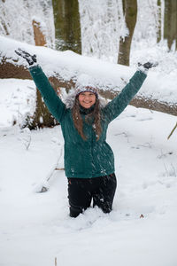 Portrait of smiling young woman standing on snow covered field