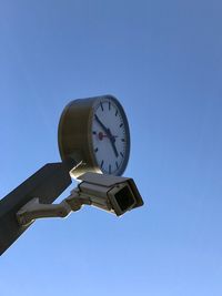 Low angle view of clock against clear blue sky