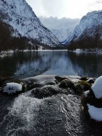 Scenic view of lake by snowcapped mountains against sky