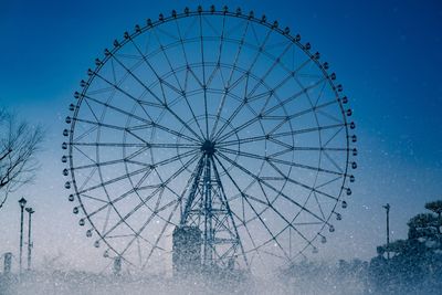 Low angle view of ferris wheel against blue sky