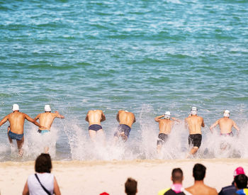 Shirtless men swimming in sea