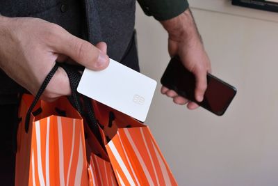 Midsection of man holding credit card and shopping bags 