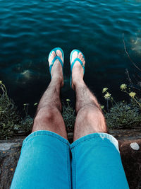 Low section of man relaxing by lake