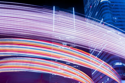 Multi colored light trails on bridge in city at night