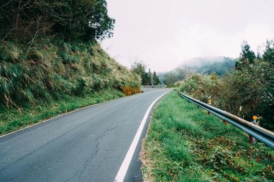 Mountain road amidst plants against clear sky