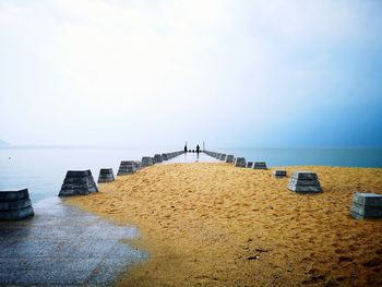 Scenic view of sea with man on pier against clear sky