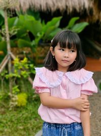 Portrait of young woman standing against plants
