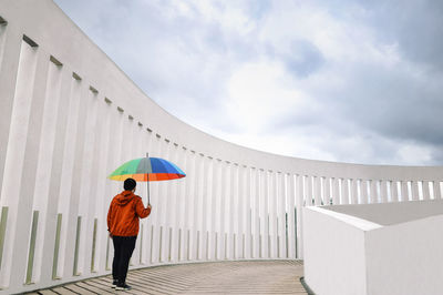 Full length of man standing with an umbrella against sky