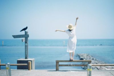 Woman standing by sea against clear sky