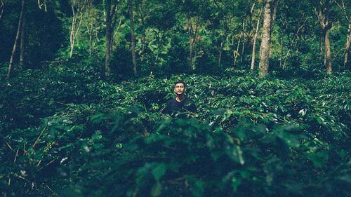 Young man with closed eyes standing amidst plants
