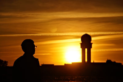 Silhouette man standing against orange sky during sunset