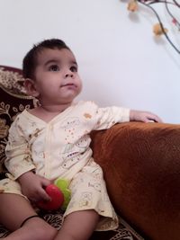 Cute baby girl sitting on bed at home