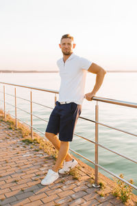 Full length of young man standing against railing