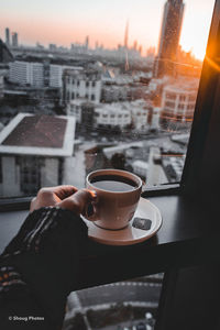 Man holding coffee cup and buildings seen through window