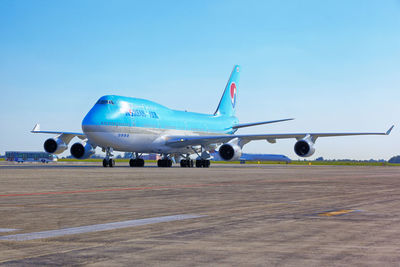 Airplane on airport runway against clear blue sky