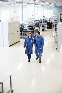 High angle view of male and female engineers discussing while walking in factory