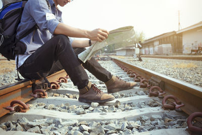 Low section of man sitting on railroad track